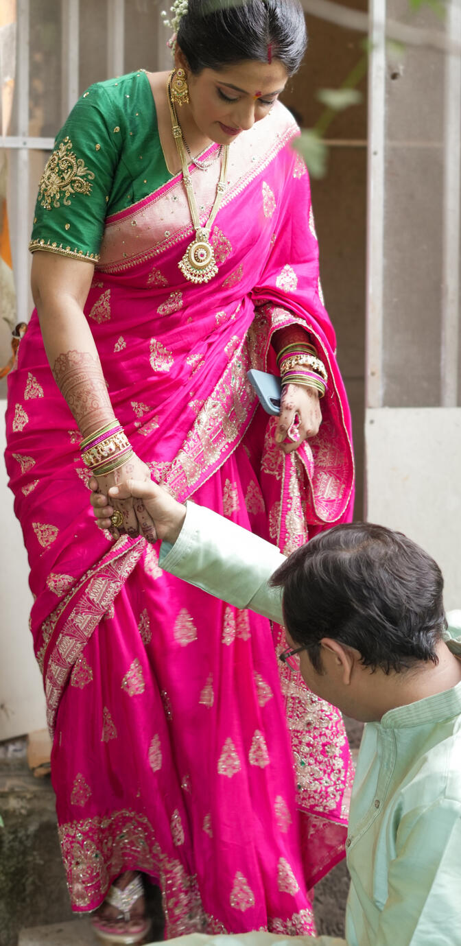 Candid wedding moment of Sandeep Rawat helping Shweta during a traditional ceremony while holding her hand.